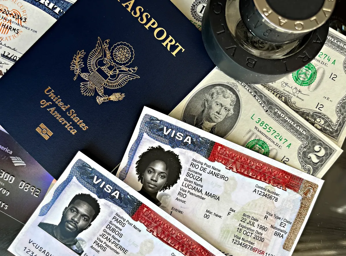 Close-up of a US passport, visa documents, currency, and stamps.