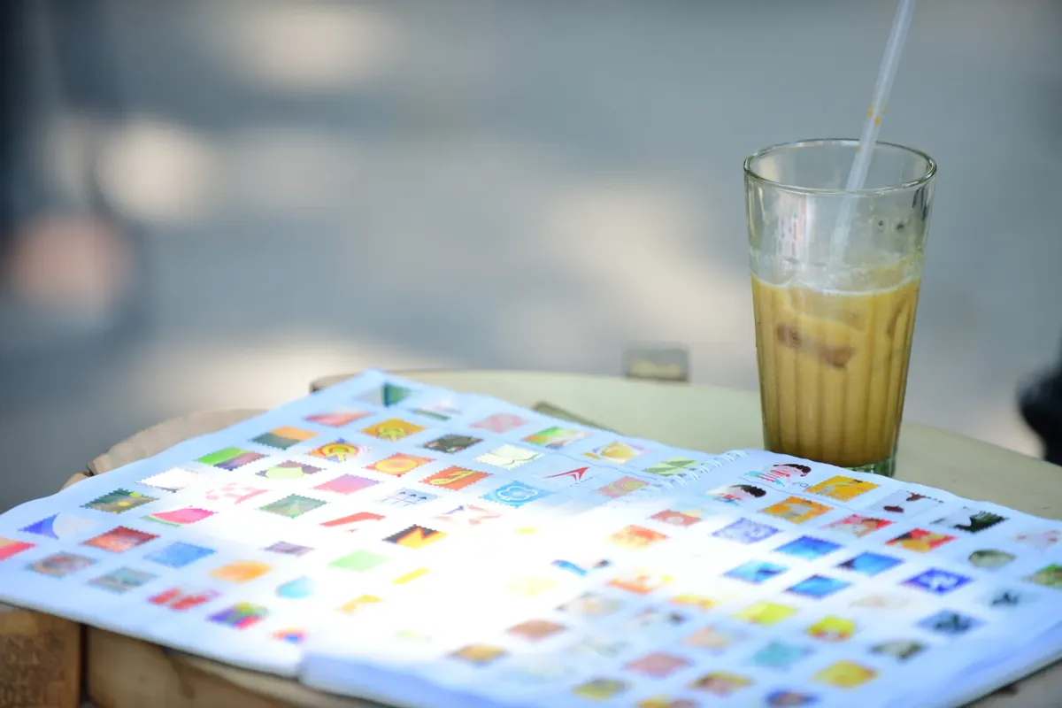 An open stamp album next to a refreshing iced coffee on a sunny day.
