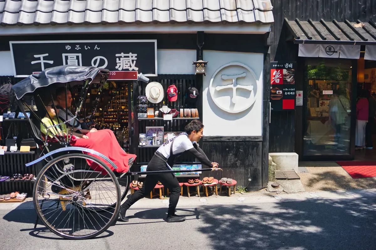 A rickshaw puller and passenger in a vibrant street setting in Japan, showcasing cultural travel experiences.