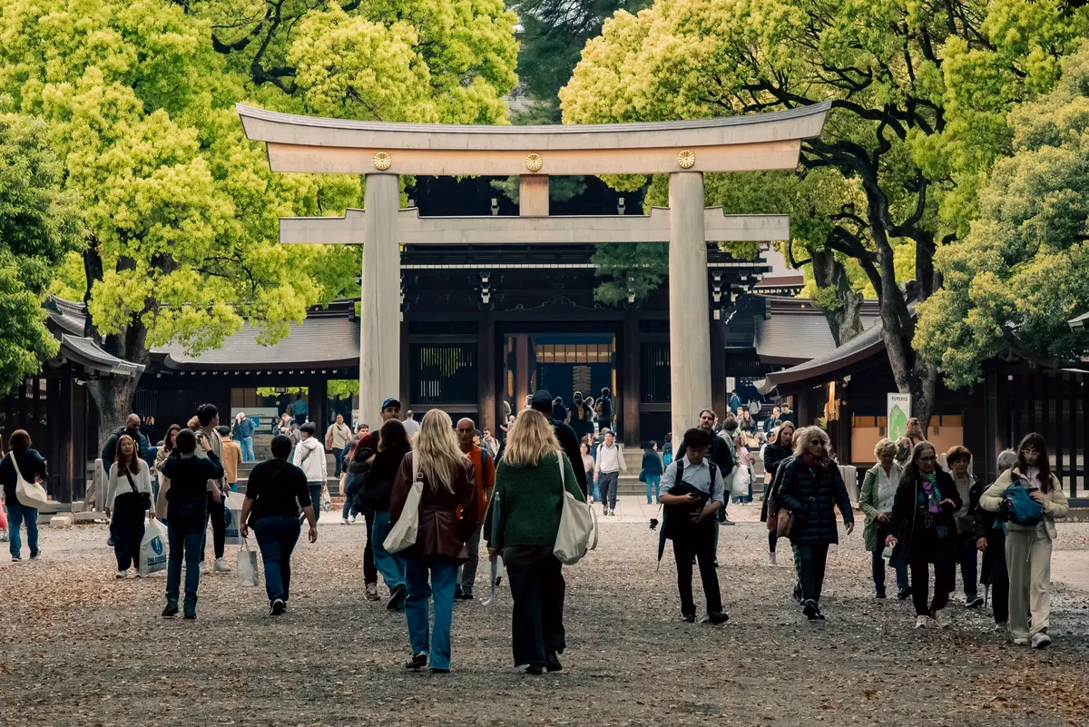 東京の Shibuya にある伝統的な鳥居に近いエネルギッシュな通りを探索する観光客。