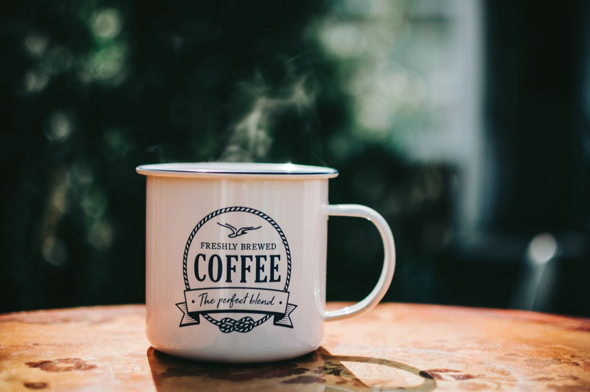 A ceramic mug filled with steaming hot cocoa, garnished with whipped cream, suggesting warmth from a winter trip.